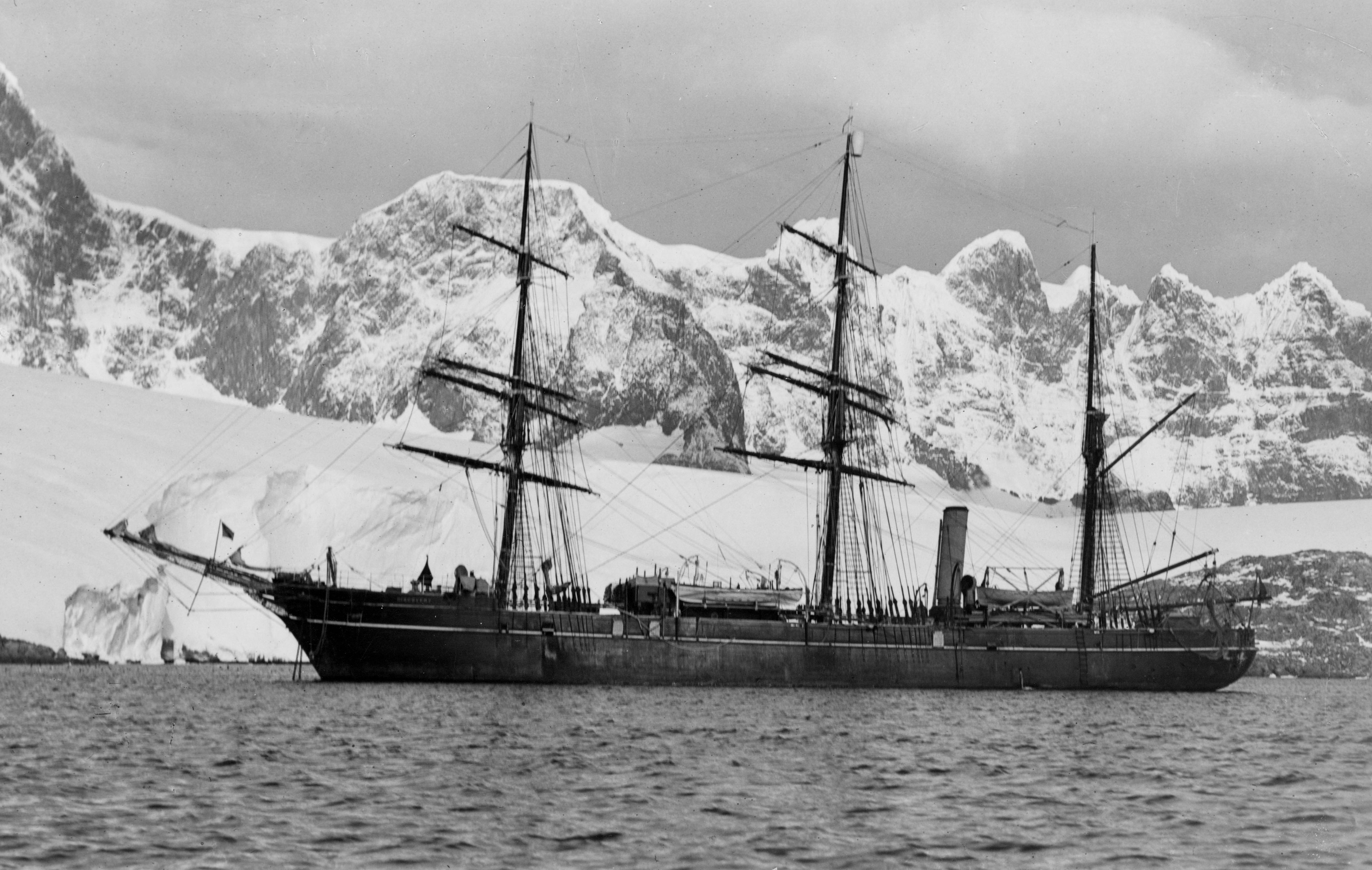 A black and white photograph of the RRS Discovery, a a barque-rigged auxiliary steamship, and the last  traditional wooden three-masted ship to be built in the United Kingdom